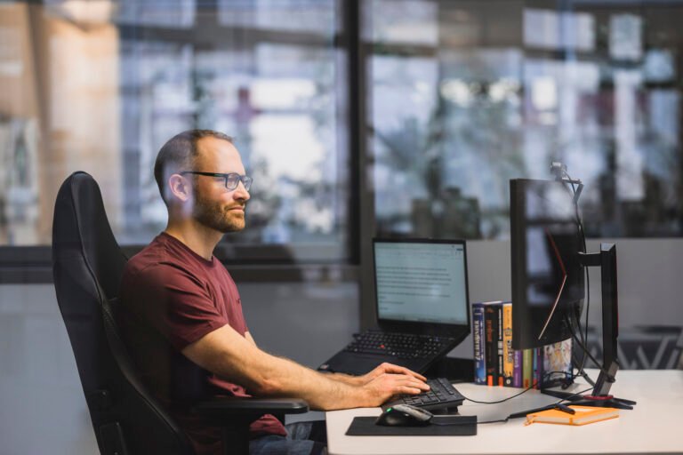 Mitarbeiter von Maigut Media in Köln arbeitet am Doppelbildschirm im modernen Büro mit urbanem Flair.