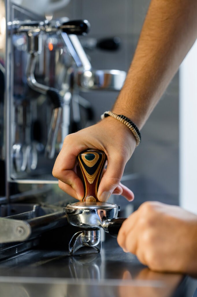 Nahaufnahme einer tätigen Person beim Bedienen einer Siebträgermaschine in einem urbanen Café in Köln.