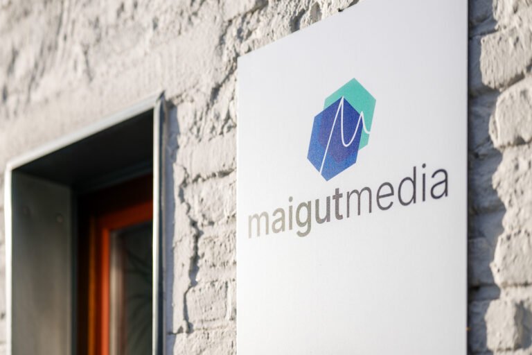 Schild des Maigut Media Büros in Ehrenfeld, Köln, an einer modernen Klinkerwand als Beispiel urbaner Agenturgestaltung.