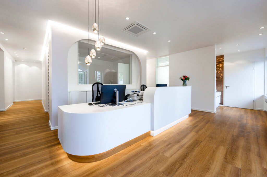 Lichtdurchfluteter Empfangsbereich einer modernen Arztpraxis mit zwei Computern.