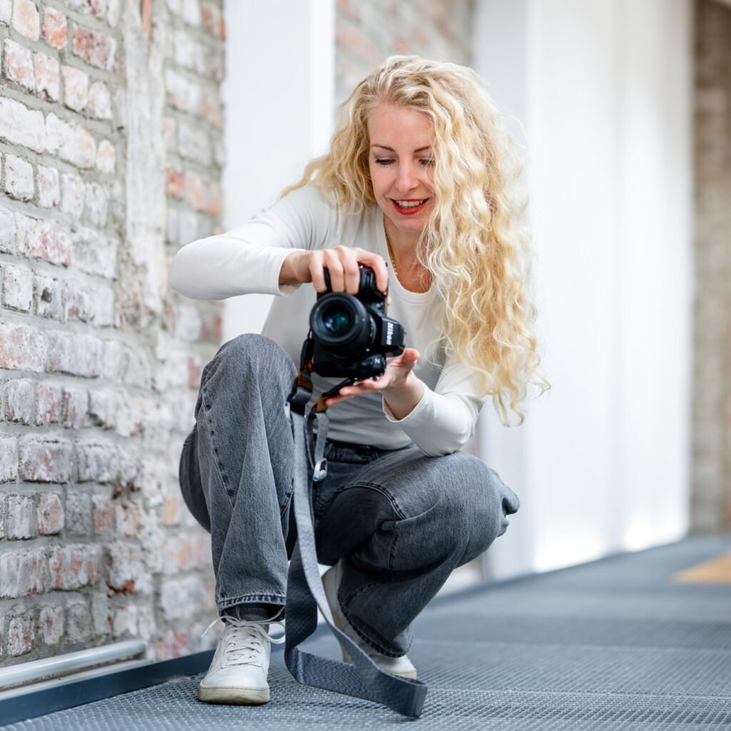 Businessfotografin Karin Maigut beim Fotografieren im Studio Köln Ehrenfeld mit Blick auf die Kamera für Ziegelwand